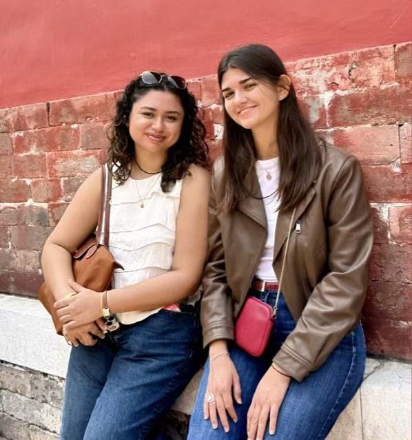 Two guests by a red palace wall